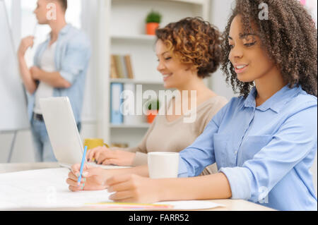 Three creative colleagues are working on their tasks. Stock Photo