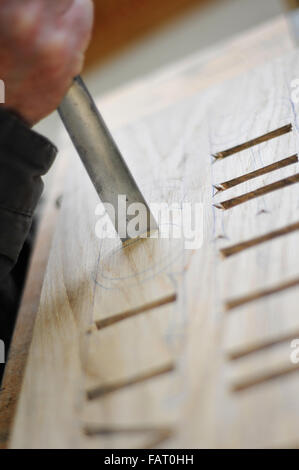 close up of curved chisel on wood block carving a letter Stock Photo