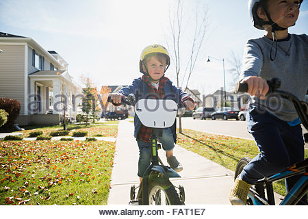 Boys riding bikes on autumn neighborhood sidewalk