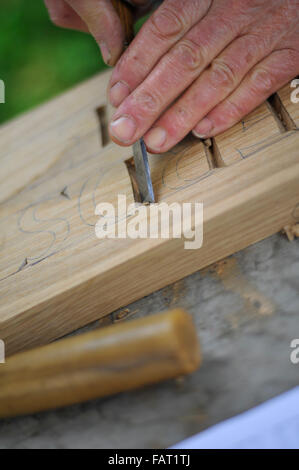 Hands carving letters in wood with chisel Stock Photo