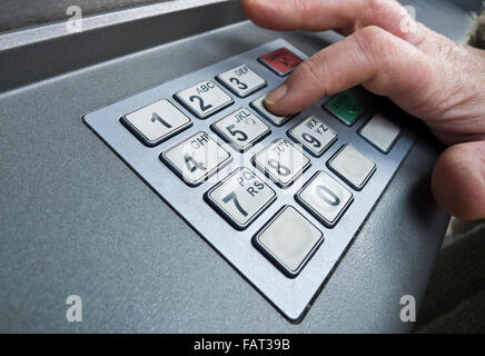 Woman keying in her PIN to a cash machine. Stock Photo