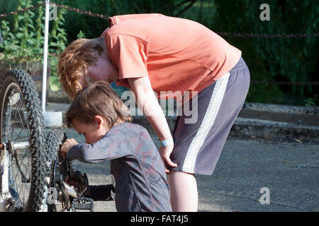 Two small boys investigate an upturned mountain bike Stock Photo