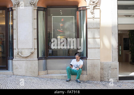 Man looking at cell phone next to shop. Stock Photo
