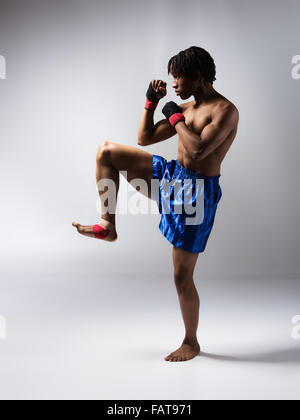 Young muscular athletic male boxer wearing blue boxing shorts and red boxing gloves. Stock Photo