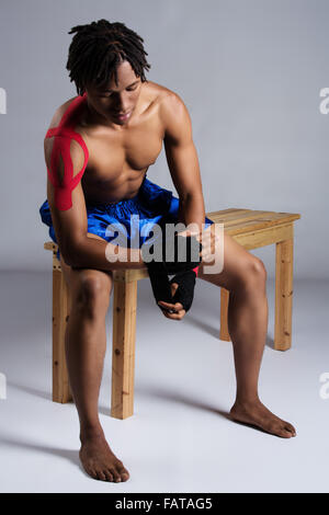 Young muscular athletic male boxer wearing blue boxing shorts and red boxing gloves. Stock Photo