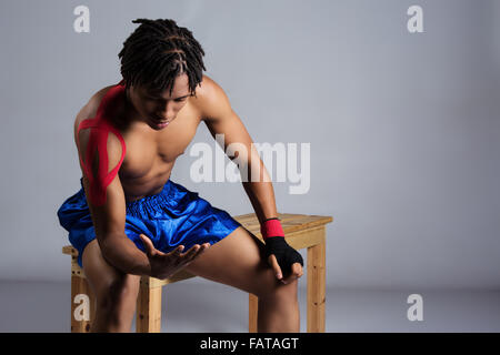 Young muscular athletic male boxer wearing blue boxing shorts and red boxing gloves. Stock Photo