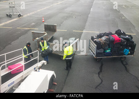 baggage handlers loading suitcases and bags onto plane Stock Photo