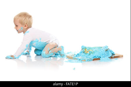 A one year old baby boy smashing a blue iced birthday cake on a wooden board. Image is isolated on a white background. Stock Photo