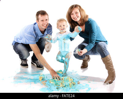 Caucasian family with mom dad and baby boy. A one year old baby boy smashing a blue iced birthday cake on a wooden board. Stock Photo