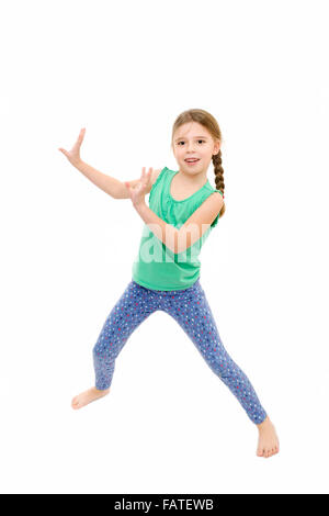 young girl wearing blue leggings and green vest dancing on white background Stock Photo