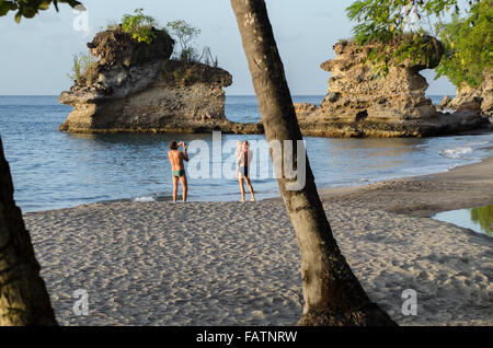 a guy photographs another holding a toddler on beach in soufriere st lucia Stock Photo