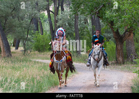 Warriors in Comanche clothing riding their horses on a path through the forest, New Mexico Stock Photo