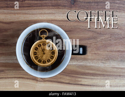offee Time Concept - vintage watch inside coffee mug showing 5 minutes to 12 o’clock on wooden table with copy space Stock Photo