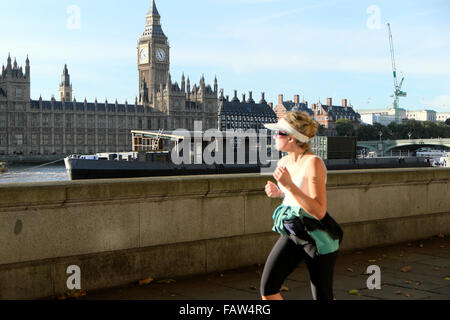 A female jogging woman jogger on the South Bank of the River Thames with view of Big Ben and Houses of Parliament in London England UK  KATHY DEWITT Stock Photo