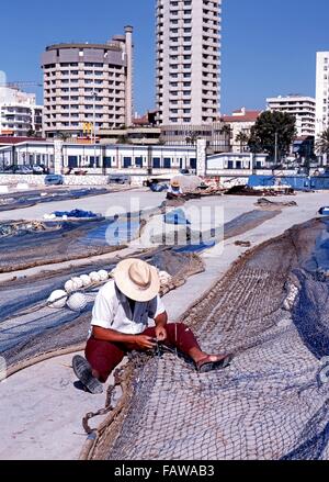 Spanish fishermen sitting on floor mending their fishing nets in the harbour area, Fuengirola, Malaga Province, Andalusia, Spain Stock Photo
