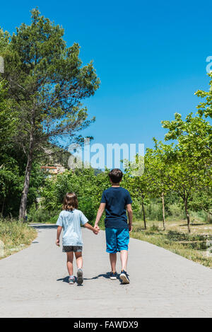 Little boy and girl walking hand in hand in the park Stock Photo