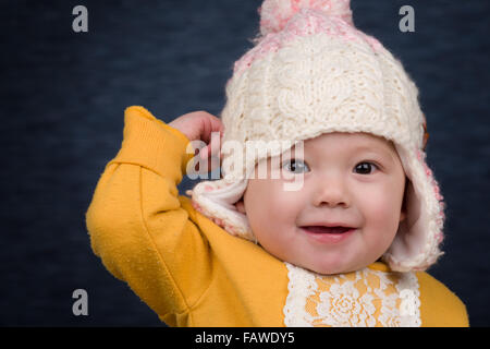 A smiling baby girl wearing a knit winter hat. Stock Photo