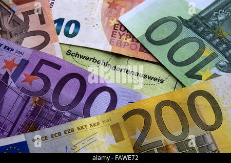 A disabled person's pass lies between Euro notes. The photo was taken on 01 December 2015. Photo: S. Steinach - NO WIRE SERVICE - Stock Photo