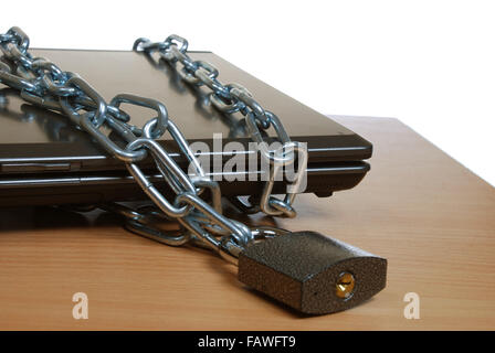 laptop, bound in a chain with a closed lock on the table. Data protection. Stock Photo