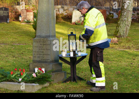 Ronneby, Sweden - December 29, 2015: Unknown male graveyard worker standing beside the memorial tombstone of unnamed persons. Sm Stock Photo