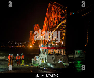Nighttime view taken in rough weather of the Forth Rail Bridge from South Queensferry with ferry and its workers. Stock Photo