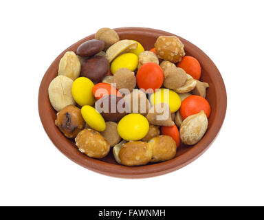 Peanut butter chips with peanuts, candy and pretzel pieces in a small bowl isolated on a white background. Stock Photo