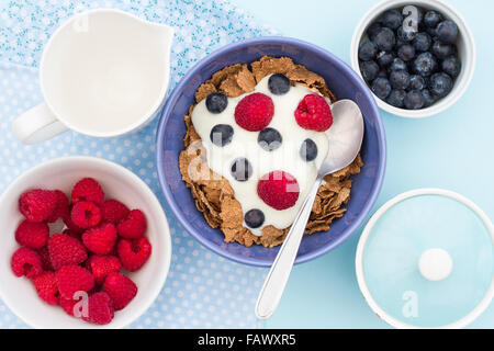 A healthy breakfast of bran flake cereal, raspberries, blueberries and natural yogurt. A view looking down onto the table from a Stock Photo