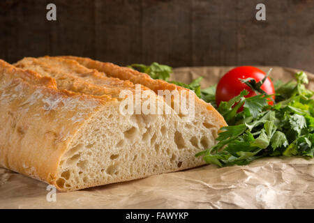 Fresh homemade bread on paper with parsley and tomato Stock Photo