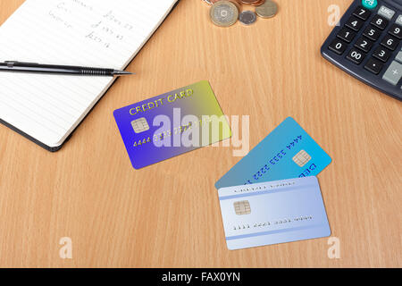 Three credit cards on a desk with a notepad, calculator and some money Stock Photo