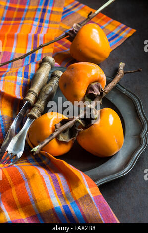 Ripe persimmons fruits on rustic background Stock Photo