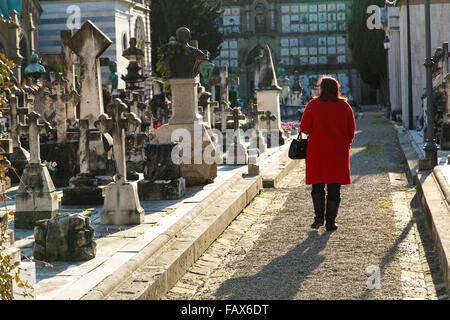 Woman in red coat soberly walking through cemetery in Florence, Italy. Stock Photo