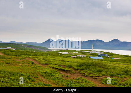 Buildings and street lights of Sand Point with King Cove and Unga Island Mountains in the background, Southwestern Alaska, USA, Summer Stock Photo