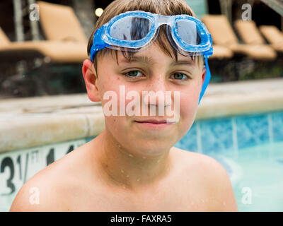 Close up portrait of teenage boy with swimming goggles in pool
