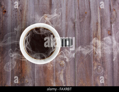 Coffee mug placed on wooden table with steaming hot black coffee Stock Photo