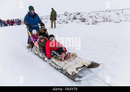 Elementary school children ride a sled pulled by sled dogs around the lagoon, Barrow, North Slope, Arctic Alaska, USA, Winter