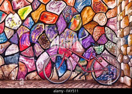 Red bicycle against colourful, abstract painted wall. Stock Photo