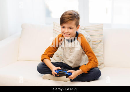 happy boy with joystick playing video game at home Stock Photo