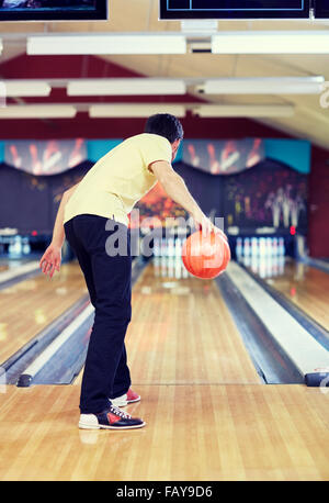 happy young man throwing ball in bowling club Stock Photo