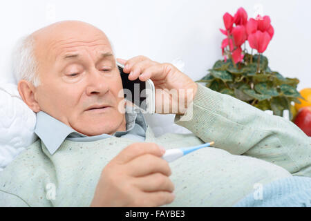 Despondent weary aged man calls up his relatives. Stock Photo