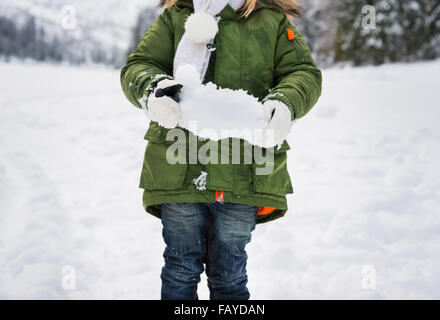 Winter outdoors can be fairytale-maker for children or even adults. Closeup on snow in hands of child in green coat. Stock Photo