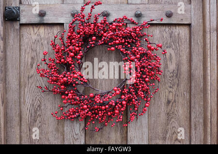 red berry style christmas wreath hanging on door Stock Photo