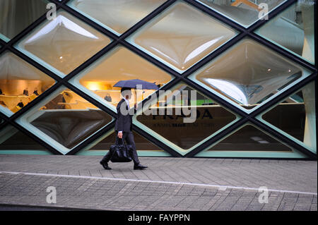 Man with umbrella walking in front of the Prada store in Omotesando Tokyo Japan Stock Photo