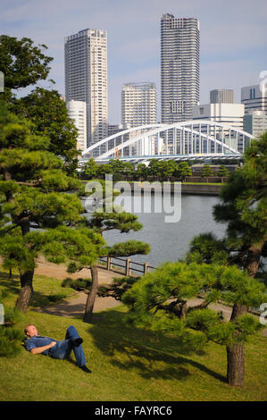 Boy lying on the grass in Hama Rikyu Gardens Tokyo Japan Stock Photo