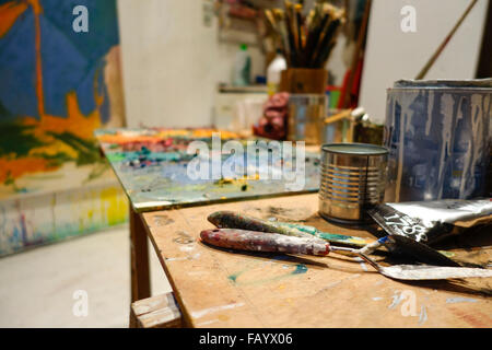 Two palette knifes in an artist studio with paint and painters table. Stock Photo