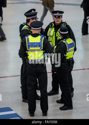 A CCTV camera watches from above as officers guard Victoria Station. The Metropolitan Police are posting more officers in Underground Stations following the suspected terrorist attack at Leytonstone Underground Station.  Featuring: Community Support Offic Stock Photo