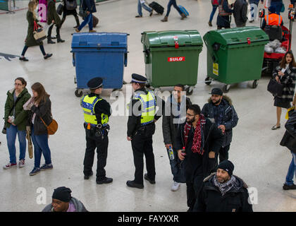 A CCTV camera watches from above as officers guard Victoria Station. The Metropolitan Police are posting more officers in Underground Stations following the suspected terrorist attack at Leytonstone Underground Station.  Featuring: Community Support Offic Stock Photo