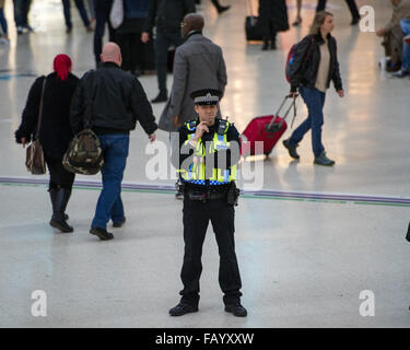 A CCTV camera watches from above as officers guard Victoria Station. The Metropolitan Police are posting more officers in Underground Stations following the suspected terrorist attack at Leytonstone Underground Station.  Featuring: Community Support Offic Stock Photo