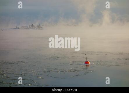 Small red buoy floating in the water that is about to freeze over in the  Baltic Sea in the archipelago of Helsinki, Finland. Stock Photo