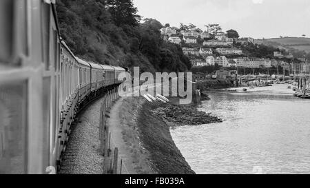 7827 Lydham Manor hauls a train along the banks of the River Dart to Kingswear station on the Dartmouth Steam Railway, Devon Stock Photo