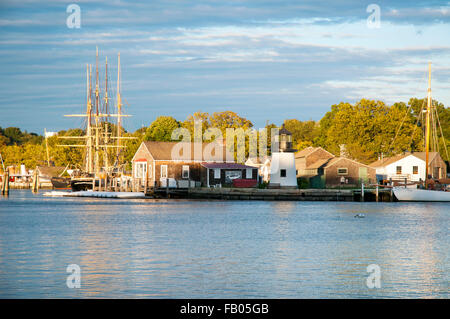 Sun setting by Mystic Seaport, across the river, an outdoor recreated 19th century village and educational maritime museum with replica of lighthouse. Stock Photo